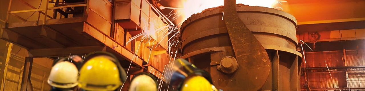 제철 공정 공장에서 중장비를 지켜보고 있는 작업자들