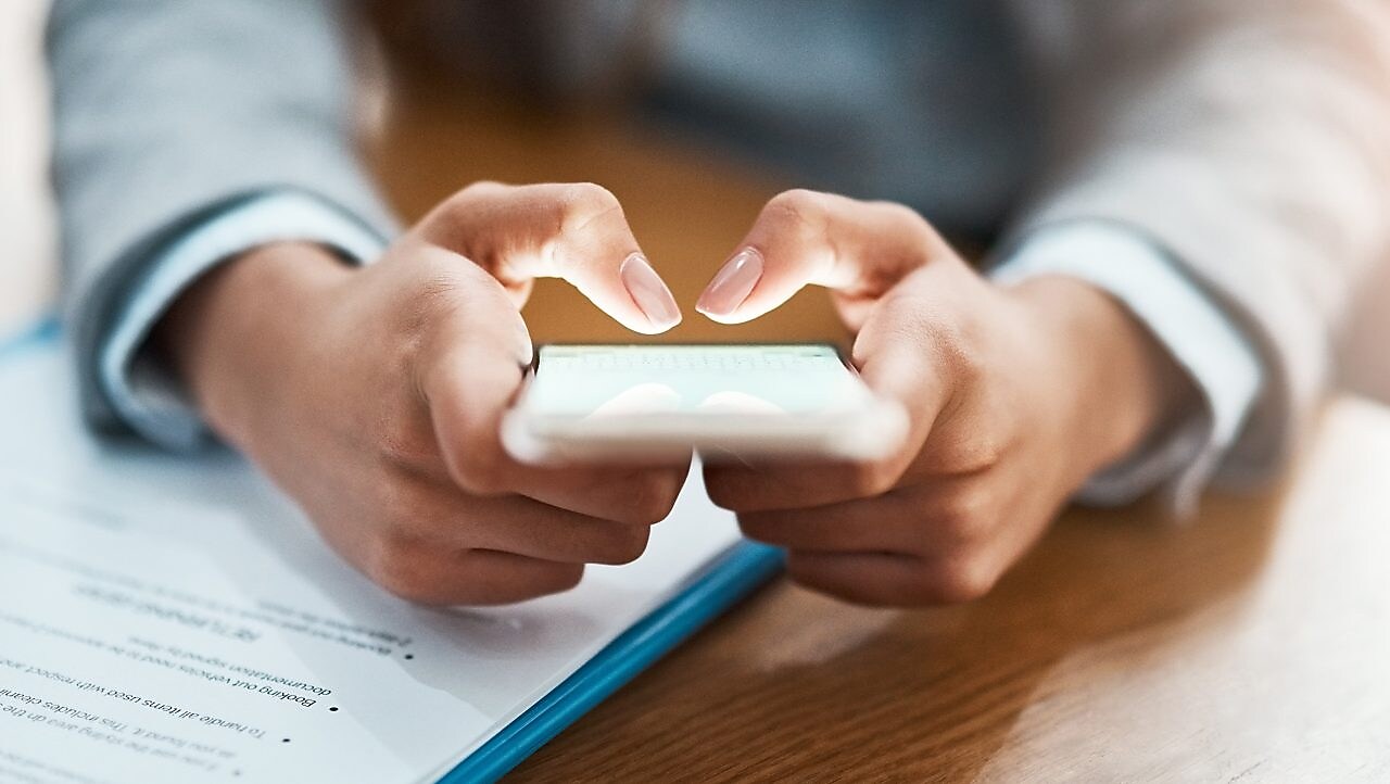 Two hands shown using a mobile device to send an email