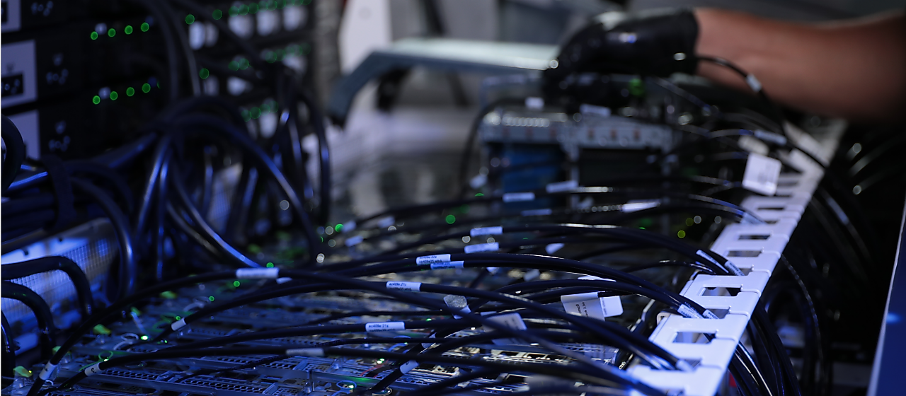 컴퓨터 시스템에 연결된 다양한 전선 옆에 장갑을 낀 손.