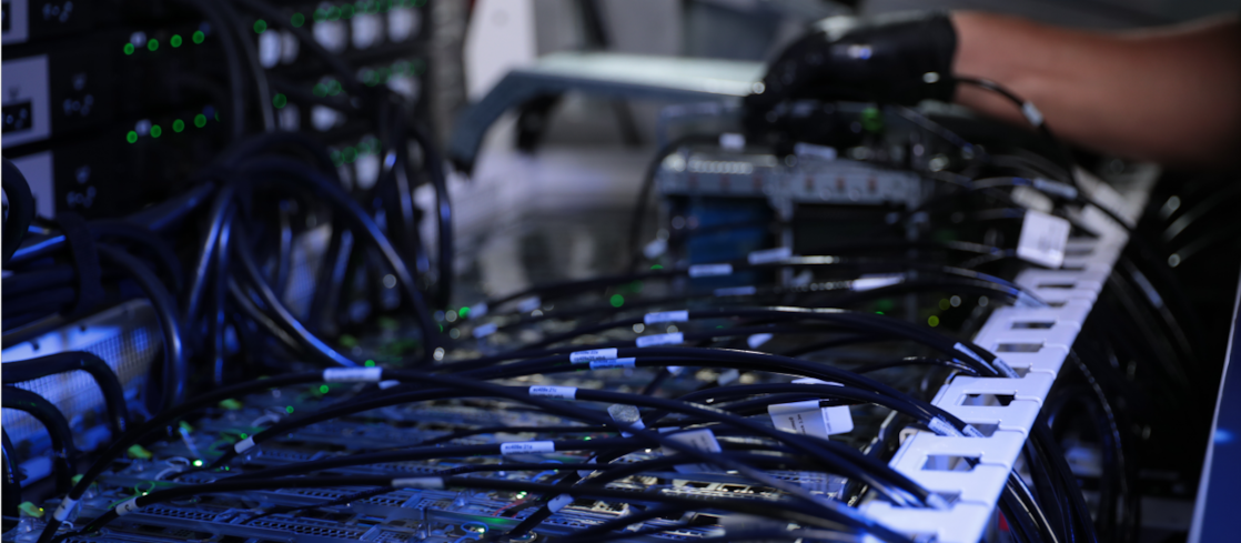 컴퓨터 시스템에 연결된 다양한 전선 옆에 장갑을 낀 손.