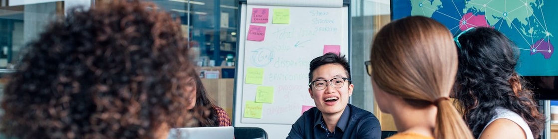 Four business people sitting around a round table reading documents, grey and yellow carpet