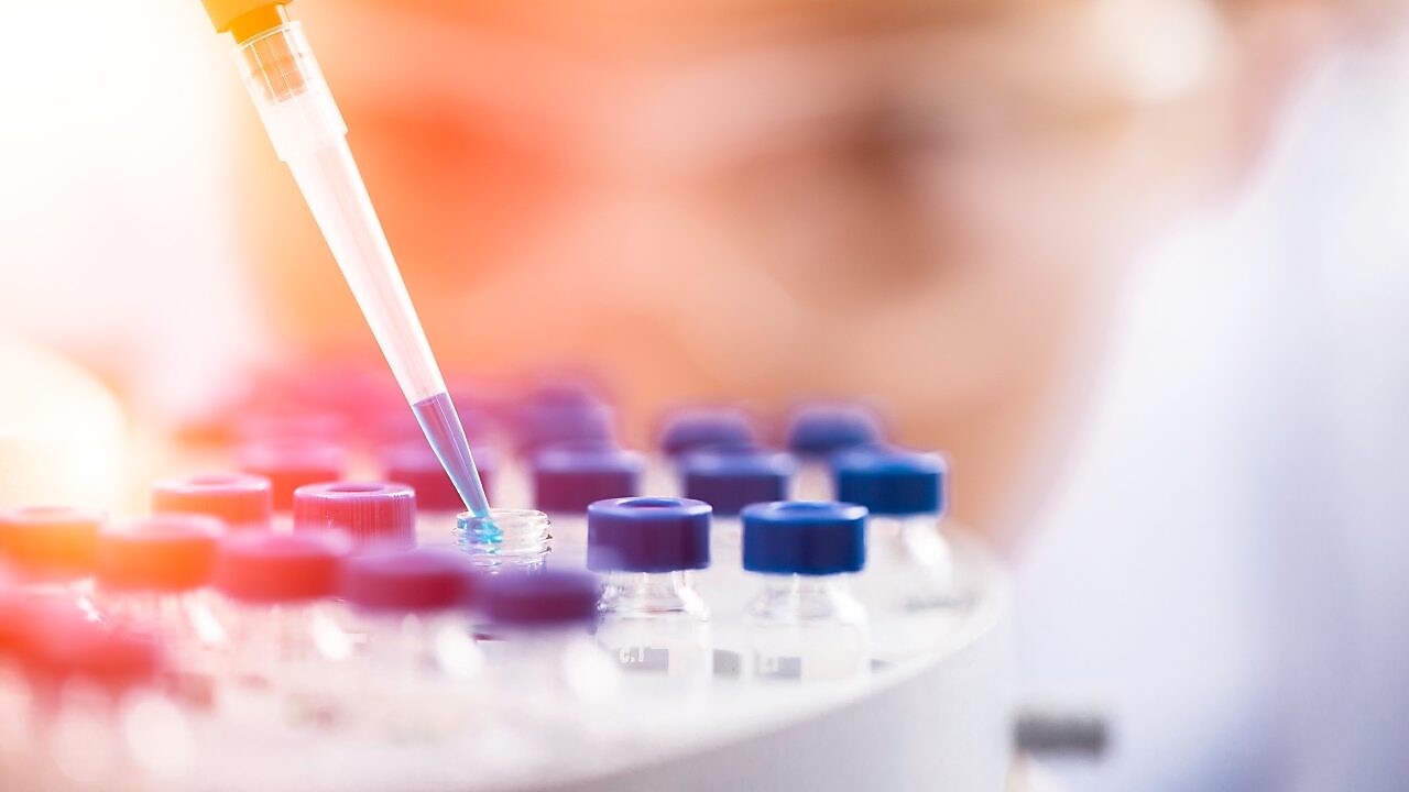 Liquid being poured into a plastic funnel by a shell scientist in a laboratory