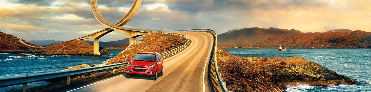 Red car driving on the road by the river