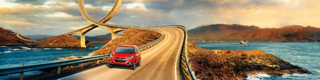 Red car driving on the road by the river