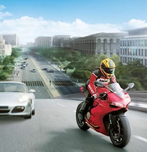 자동차와 건물을 배경으로 하고 도로를 달리는 빨간색  모터사이클과 운전자